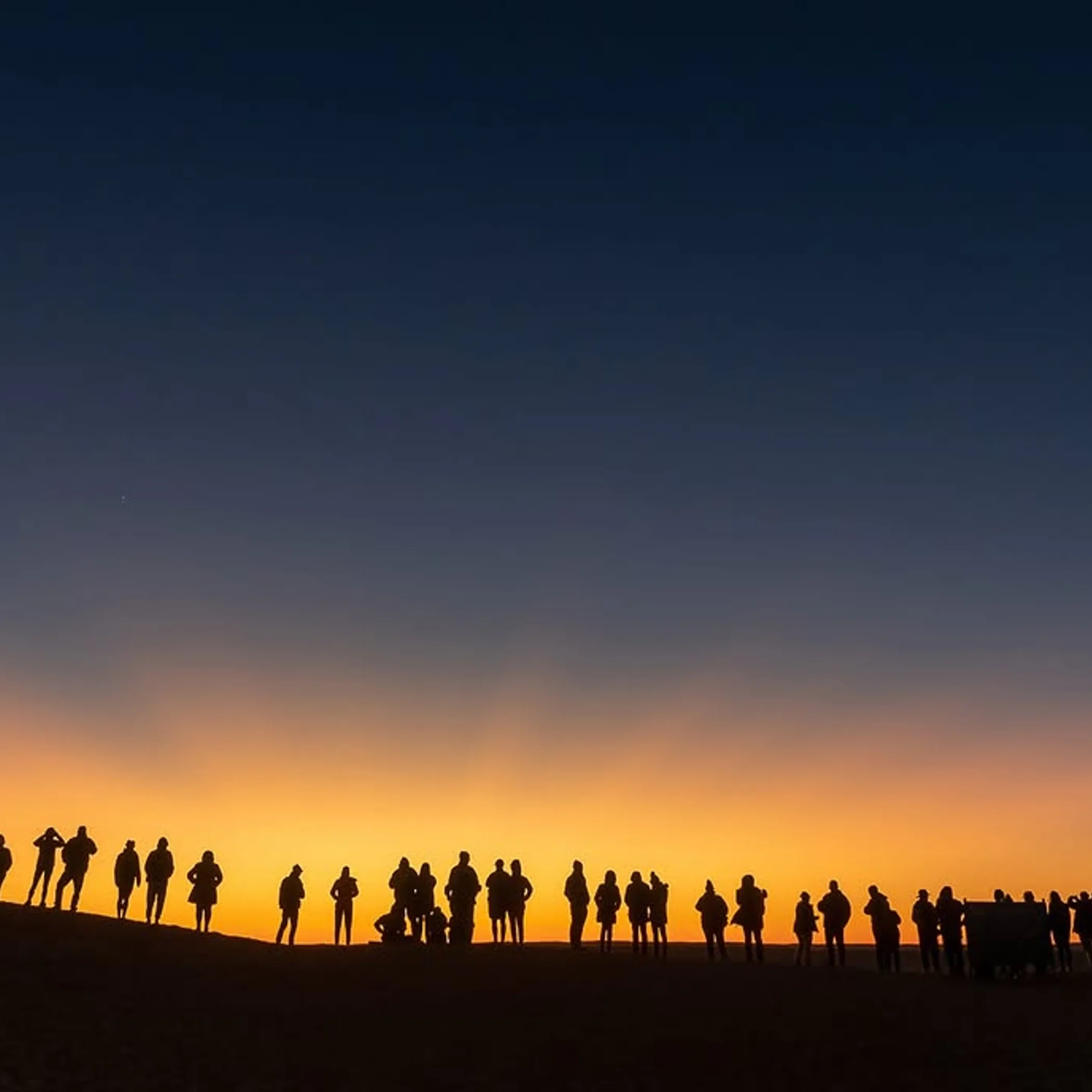 people gathering on desert dune at sunset